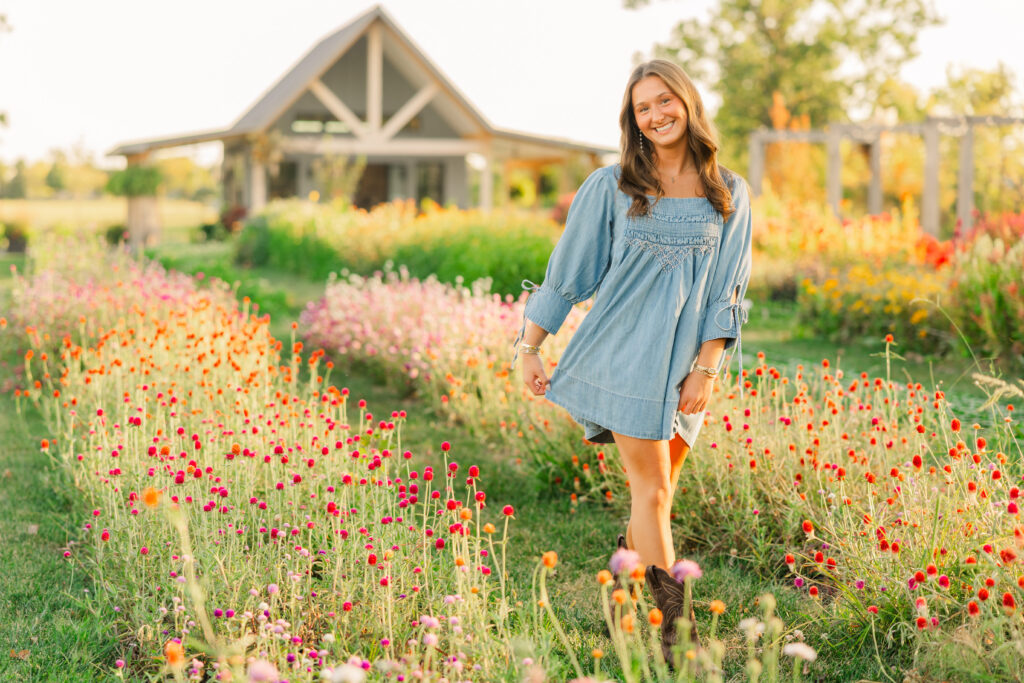 High school senior walking through rows of flowers at Sweet Pea Flower Farm in Noblesville, Indiana during golden hour. 
