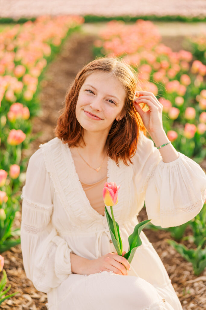 senior photo session with soft pink and yellow ombre tulips and a female in a flowy cream dress 